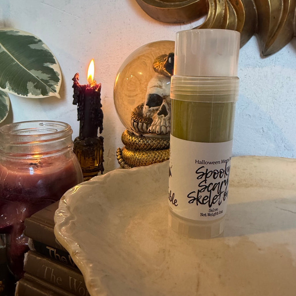 Spooky Scary Skeletons salve stick angled view with skull snow globe and vintage books