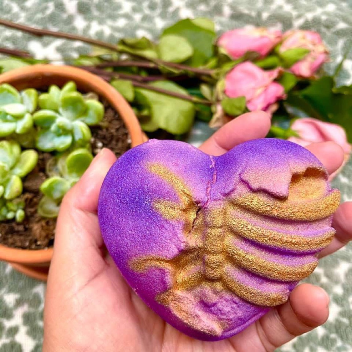 VooDoo Queen Valentine bath bomb held in hand, showing its large size and gold ribcage detail
