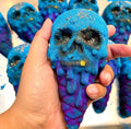 Berrycide bath bomb held close, blue skull with gold tooth and glitter over a purple cone