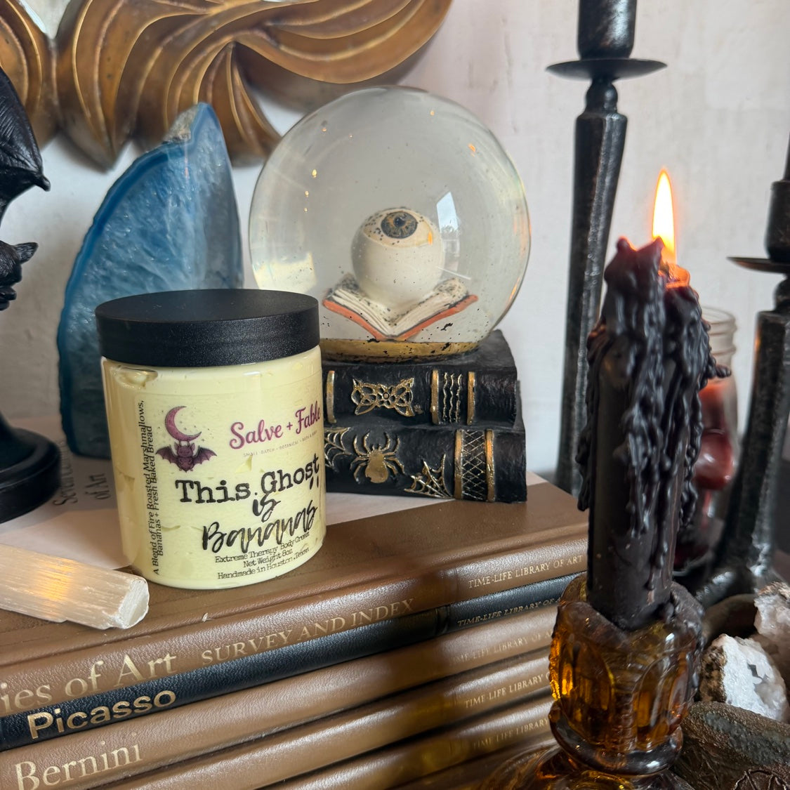 This Ghost Is Bananas cream jar angled in a styled vintage scene with lit candle