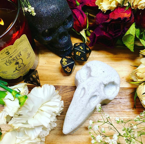 Dreadful bath bomb, a white raven skull, styled with black dice, roses and a glitter skull