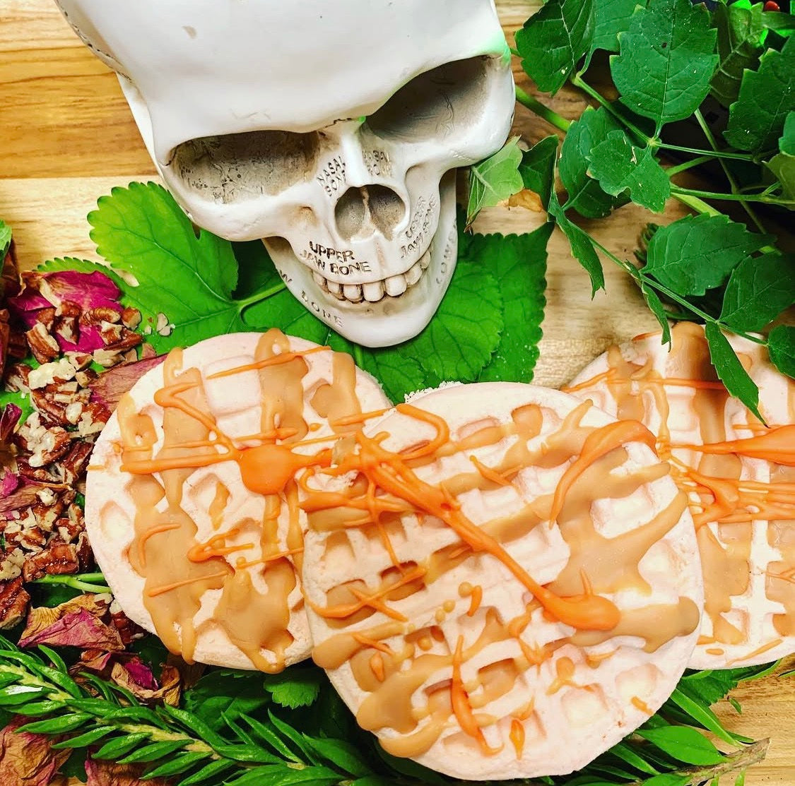 Fall Waffles bath bombs styled with a skull, green leaves and pecans
