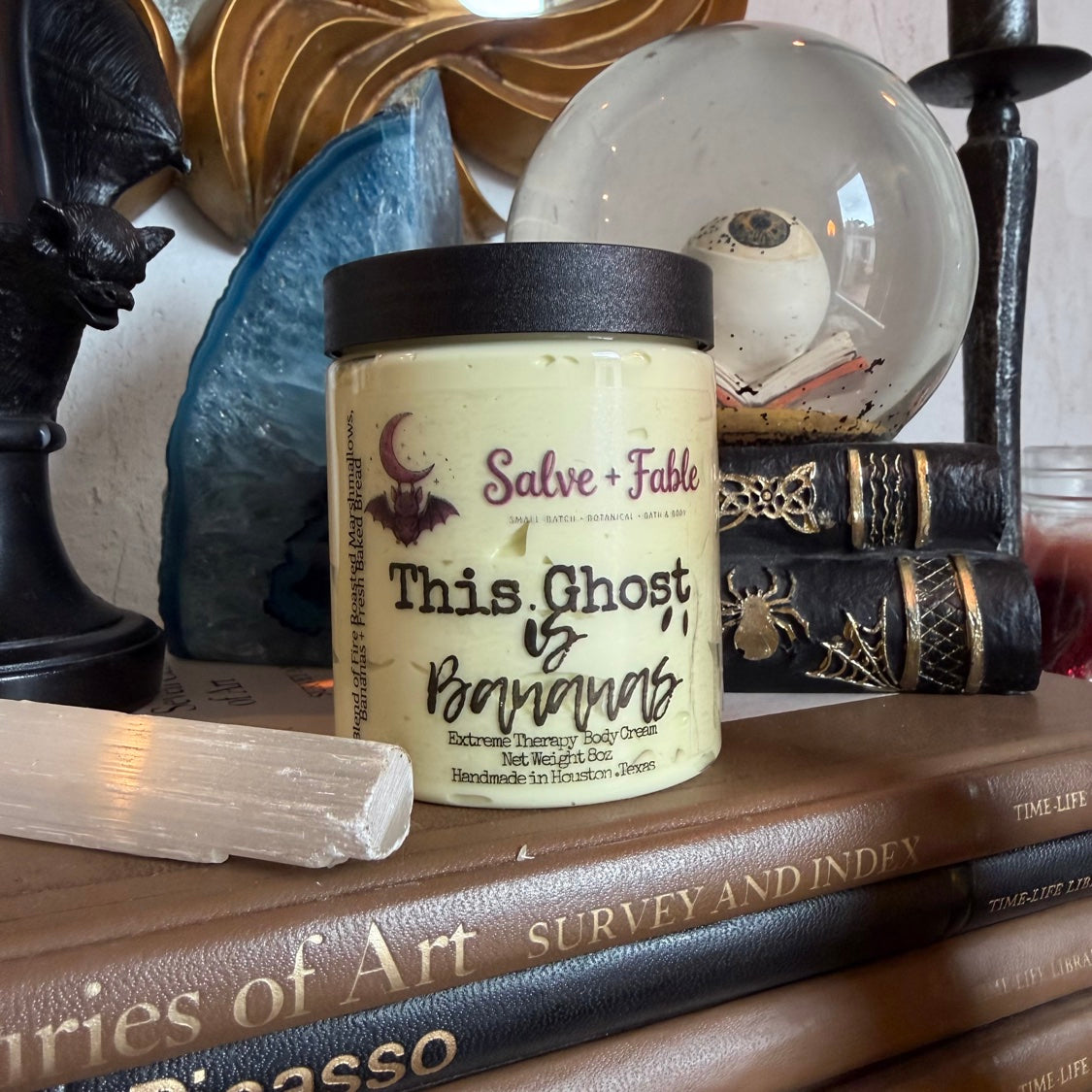 This Ghost Is Bananas Extreme Menthol Cream jar with clear label, styled on vintage art books with eyeball snow globe