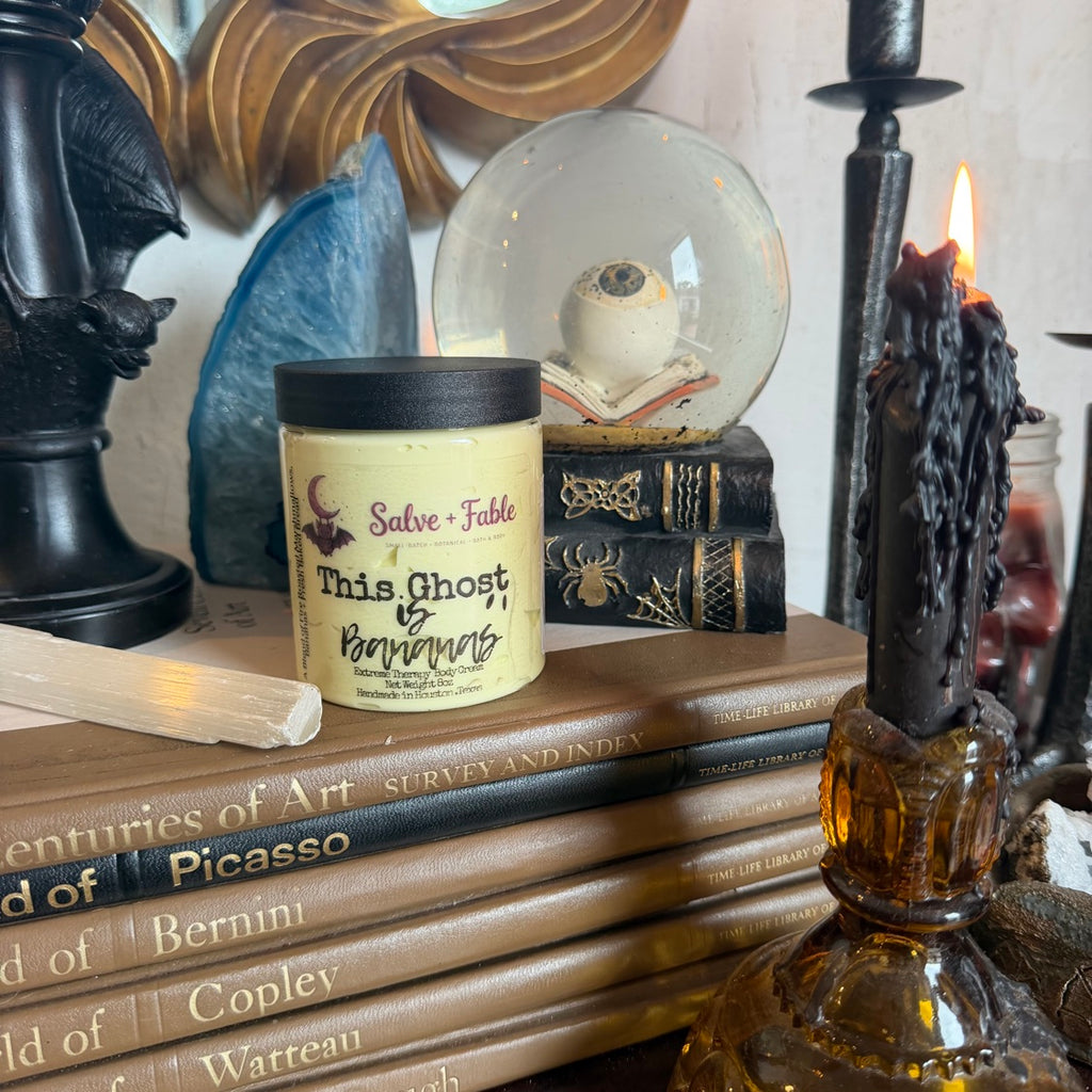 This Ghost Is Bananas cream jar in a styled scene with black dripping candle and vintage books
