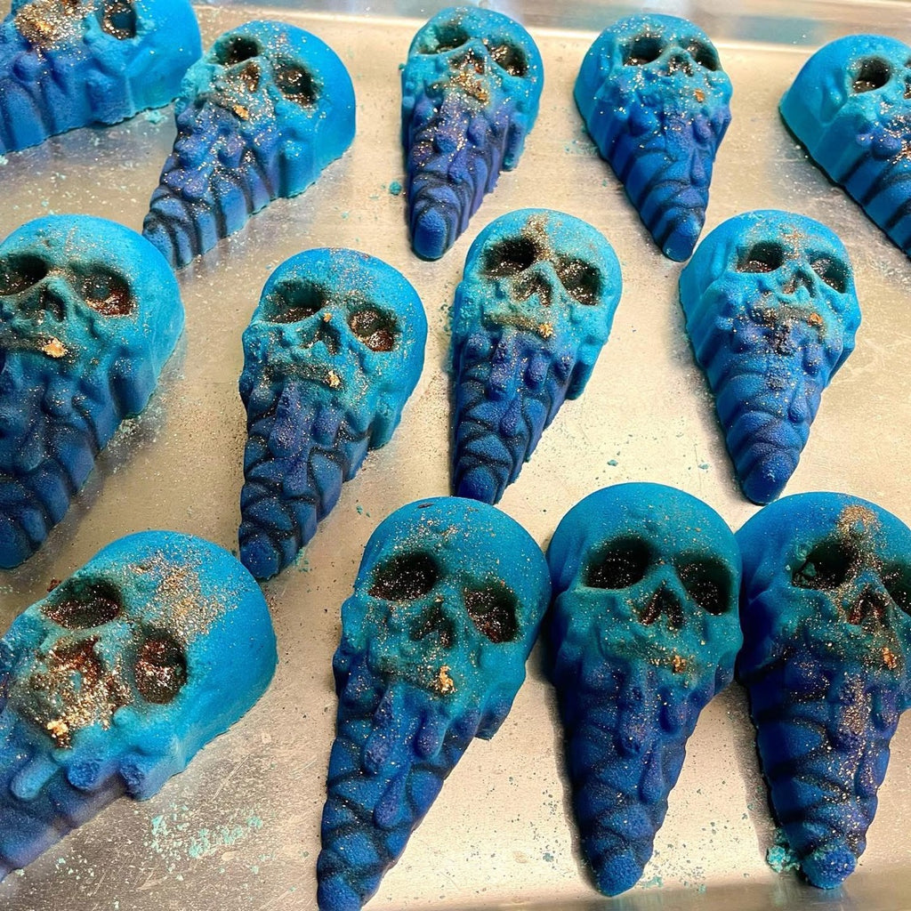 A tray of Berrycide bath bombs, blue skulls melting into purple ice cream cones with gold glitter